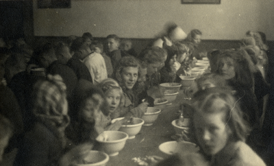 811772 Afbeelding van enkele kinderen tijdens een gezamelijke maaltijd van een gaarkeuken in een lokaal in de omgeving ...